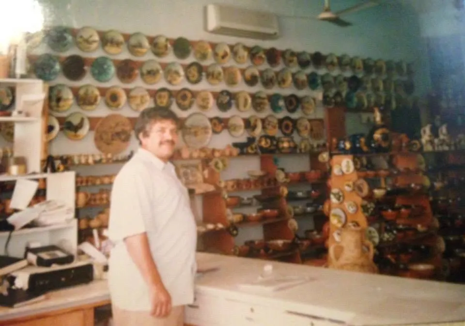 Tomrul Tomgűsehan in the Dizayn74 showroom in front of walls of hand-painted plates, Kyrenia